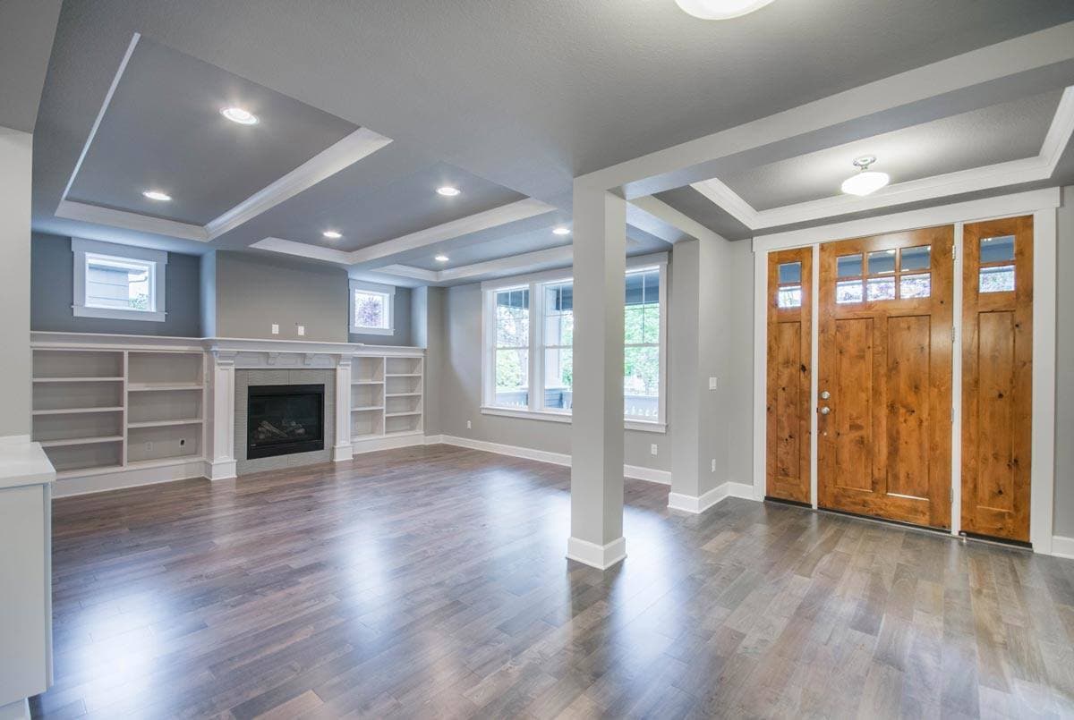 Interior view of a living area with a fireplace, built-in shelving, coffered ceiling, and double wood doors.
