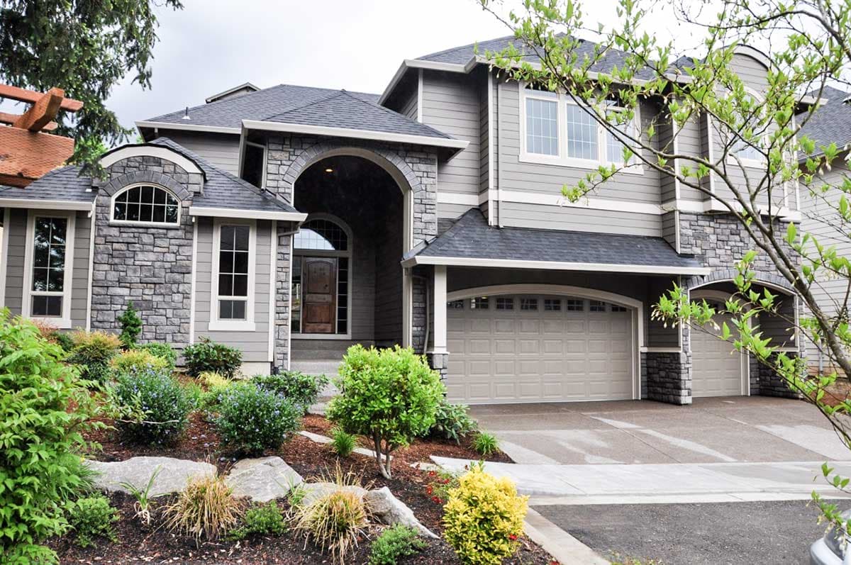 House plan exterior featuring stone accents, arched entryway, multiple gables, and a three-car garage.