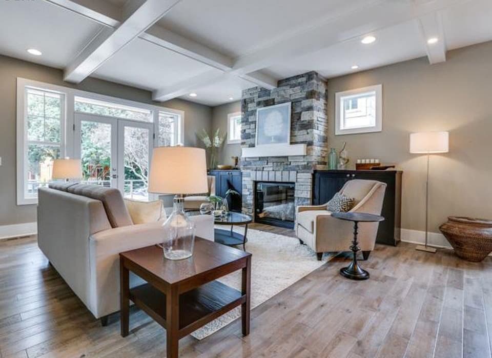 Great room with stone fireplace, coffered ceiling, and French doors leading outdoors.