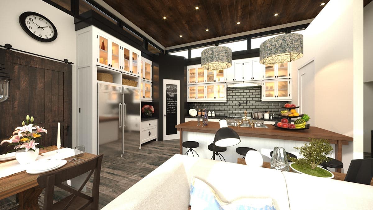 Modern kitchen and dining area with vaulted wood ceiling, white cabinetry, stainless steel appliances, island, and a sliding barn door.