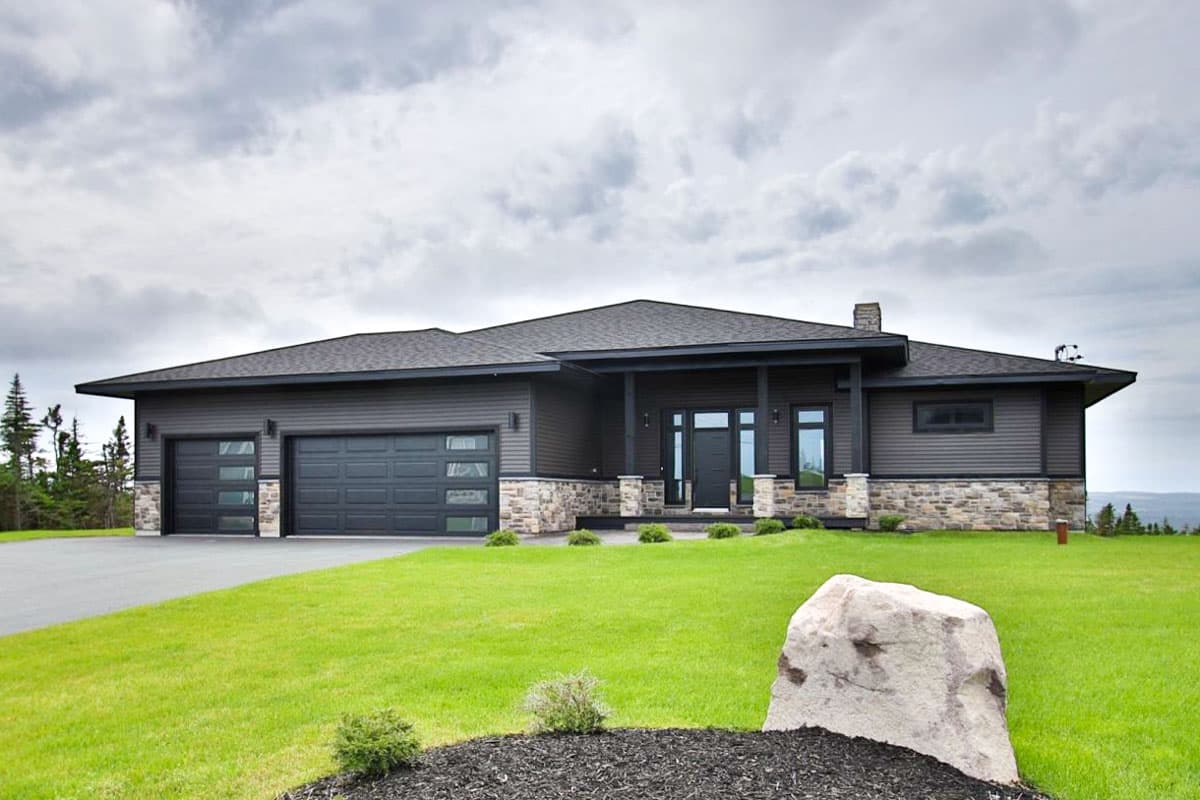 House plan exterior with two-car garage, stone veneer, and covered entry porch. Single-story, flat roof design with modern lines.