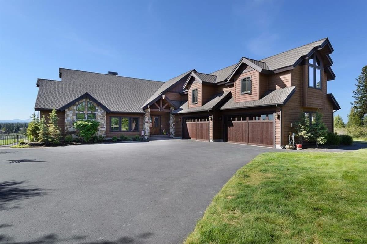 House plan exterior. Two-story home with Craftsman style. Features include multiple gables, stone accents, and a front-facing, two-car garage.