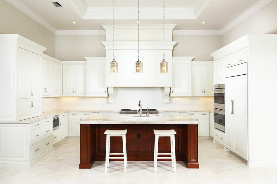 Spacious kitchen with white cabinetry, large island with seating, stainless steel appliances, and a coffered ceiling.