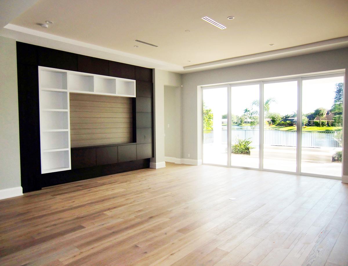 Interior view of a great room with a built-in media center and large sliding glass doors overlooking a water view.