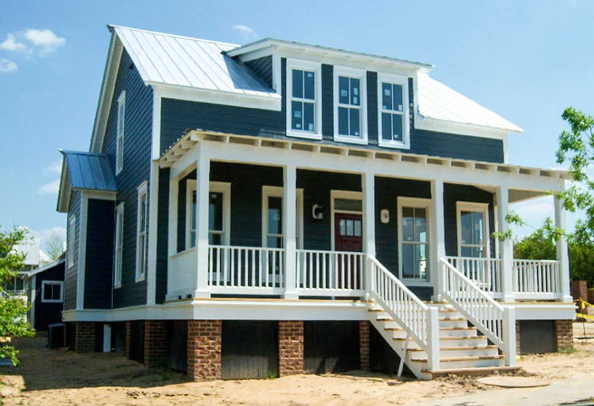 House plan exterior: Two-story home with wrap-around porch, metal roof, multiple gables, and dormer windows.