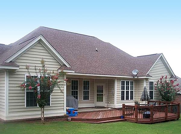 House plan exterior shows a one-story home with vinyl siding, multiple gables, a covered porch, and an elevated wooden deck.
