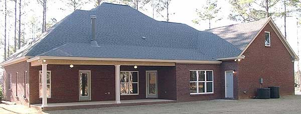 House plan exterior: One-story brick home with a covered porch, multiple windows, and a gabled roof with a dormer.