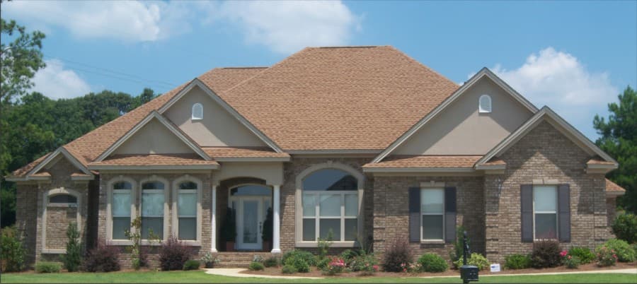 House plan exterior: One-story brick home with arched entryway, multiple gables, and a symmetrical roofline.