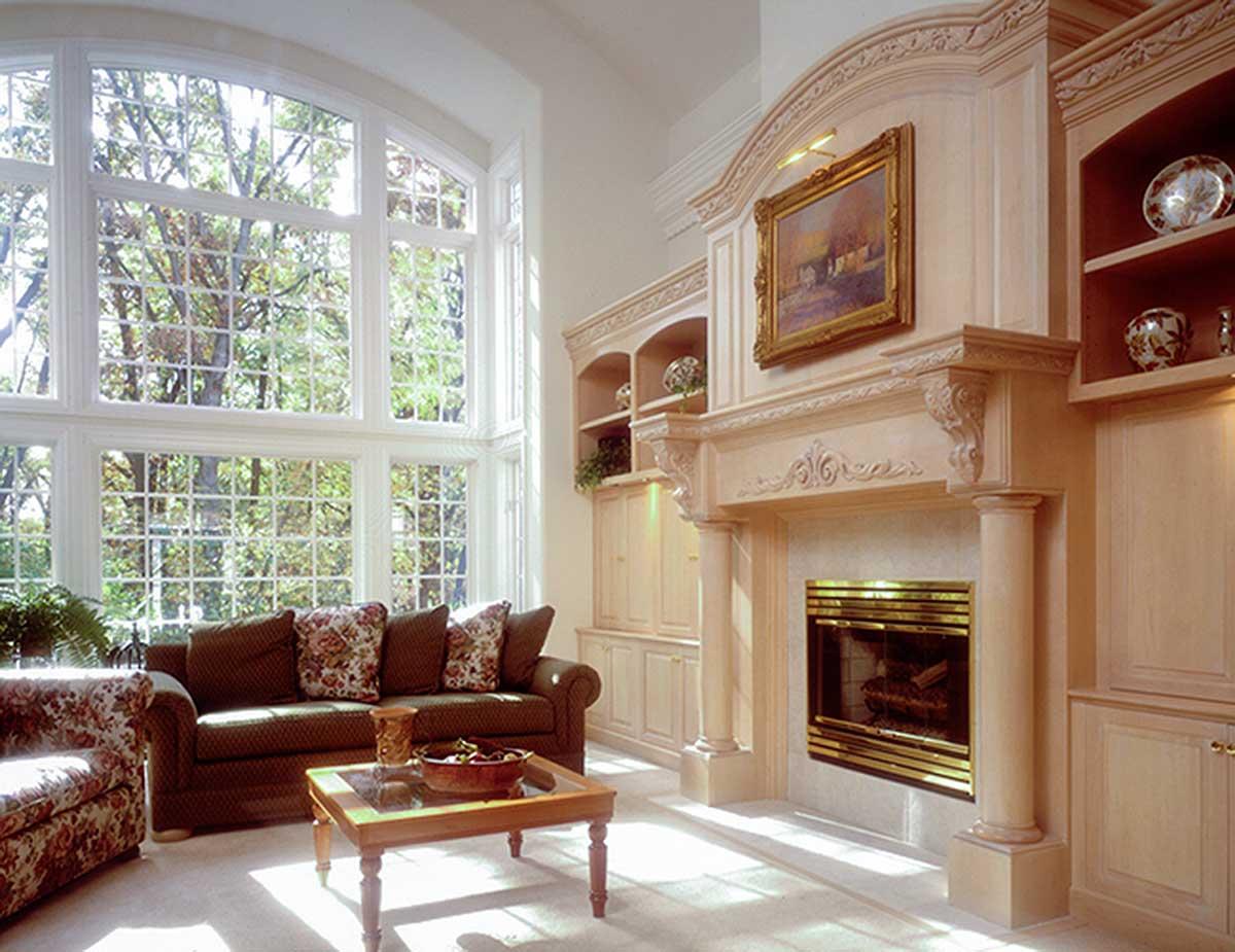 Living room with floor-to-ceiling windows, fireplace with ornate mantel, and built-in cabinetry.