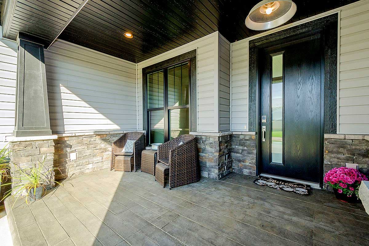 House plan exterior with covered porch, stone accents, large windows, and a dark entry door.