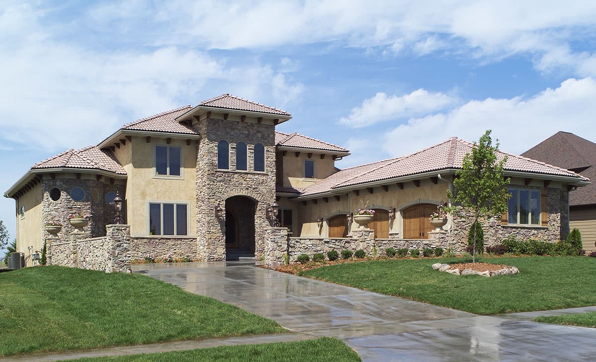 House plan exterior. Two-story Mediterranean-style house with stone accents, arched entryway, and tile roof. Includes multiple gabled sections.