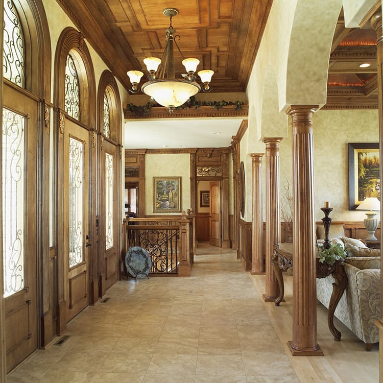 Interior hallway with coffered wood ceiling, arched entryways with decorative glass, fluted columns, and ornate railing.