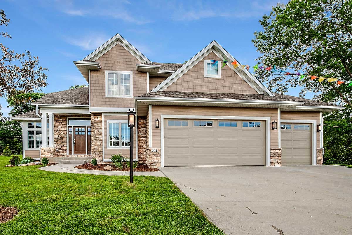 House plan exterior with two-story design, stone accents, two-car garage, and multiple gables. Features a covered entry and dormer windows.