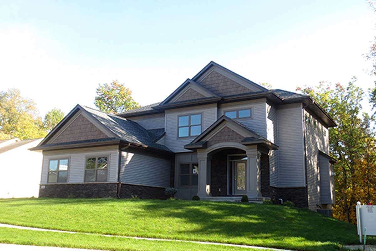 Two-story house plan exterior with gables, dormers, stone accents, and covered entry.
