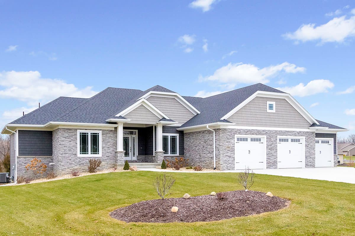 House plan exterior: Ranch style, stone and siding facade, covered entry, and a four-car garage.