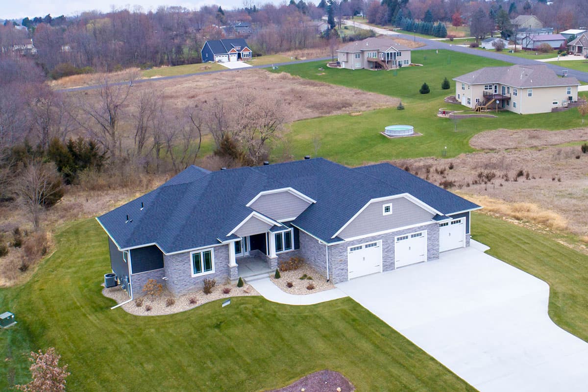 House plan exterior: Ranch-style home with three-car garage, stone accents, and covered entry porch.