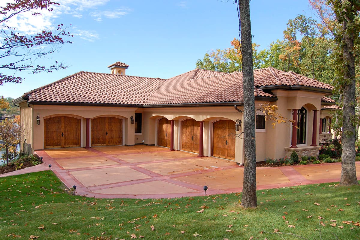 House plan exterior with tiled roof, stucco walls, six arched garage doors, and decorative columns.