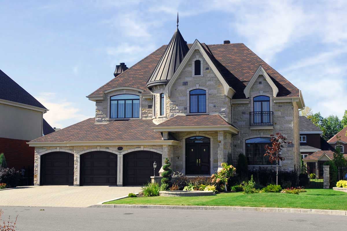 House plan exterior of a two-story stone home with a triple garage, arched entry, and conical turret.