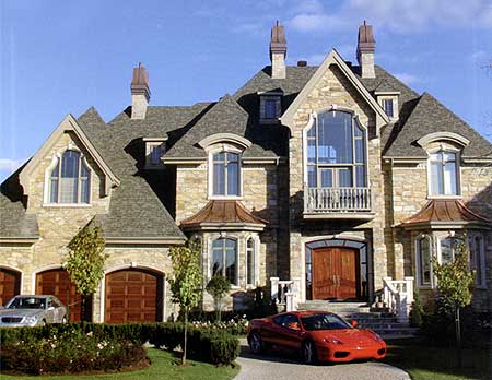 House plan exterior with stone facade, multiple gables, arched windows, copper dormers, and a central arched entryway with double doors.