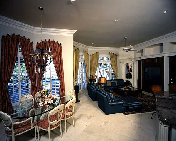 Open-concept living and dining area with glass-top dining table, sectional sofa, fireplace, and ceiling fan.