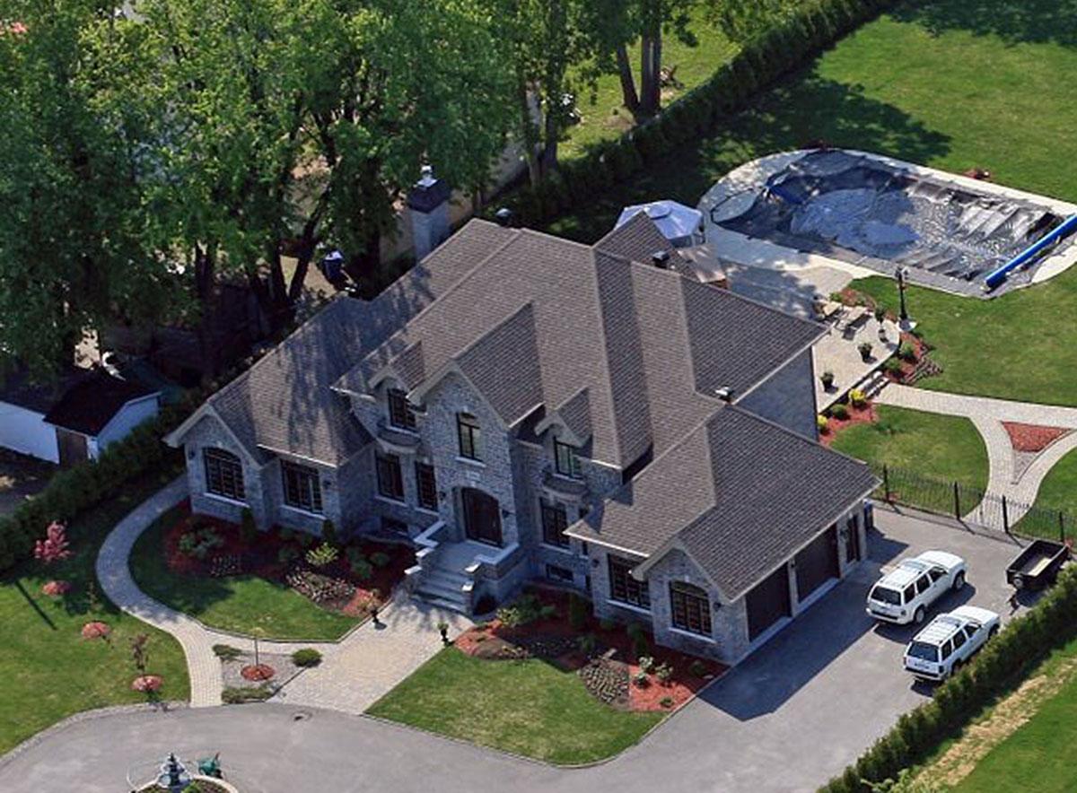House plan exterior: Two-story stone home with multiple gables, dormers, and a side-facing three-car garage.