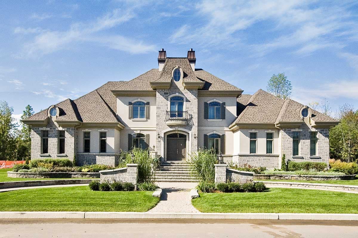 House plan exterior with a mansard roof, central dormer, stone accents, and symmetrical wings.