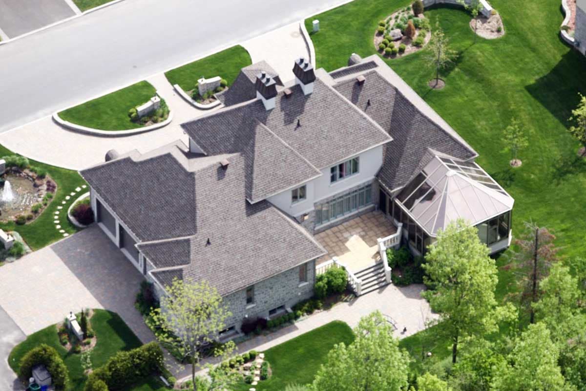 House plan exterior: two-story residence with multiple gables, attached garage, sunroom, and stone accent.