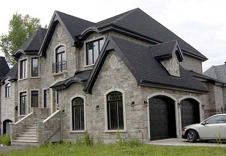 House plan exterior: French-inspired stone facade with arched windows, dormers, balconies, and a triple garage.