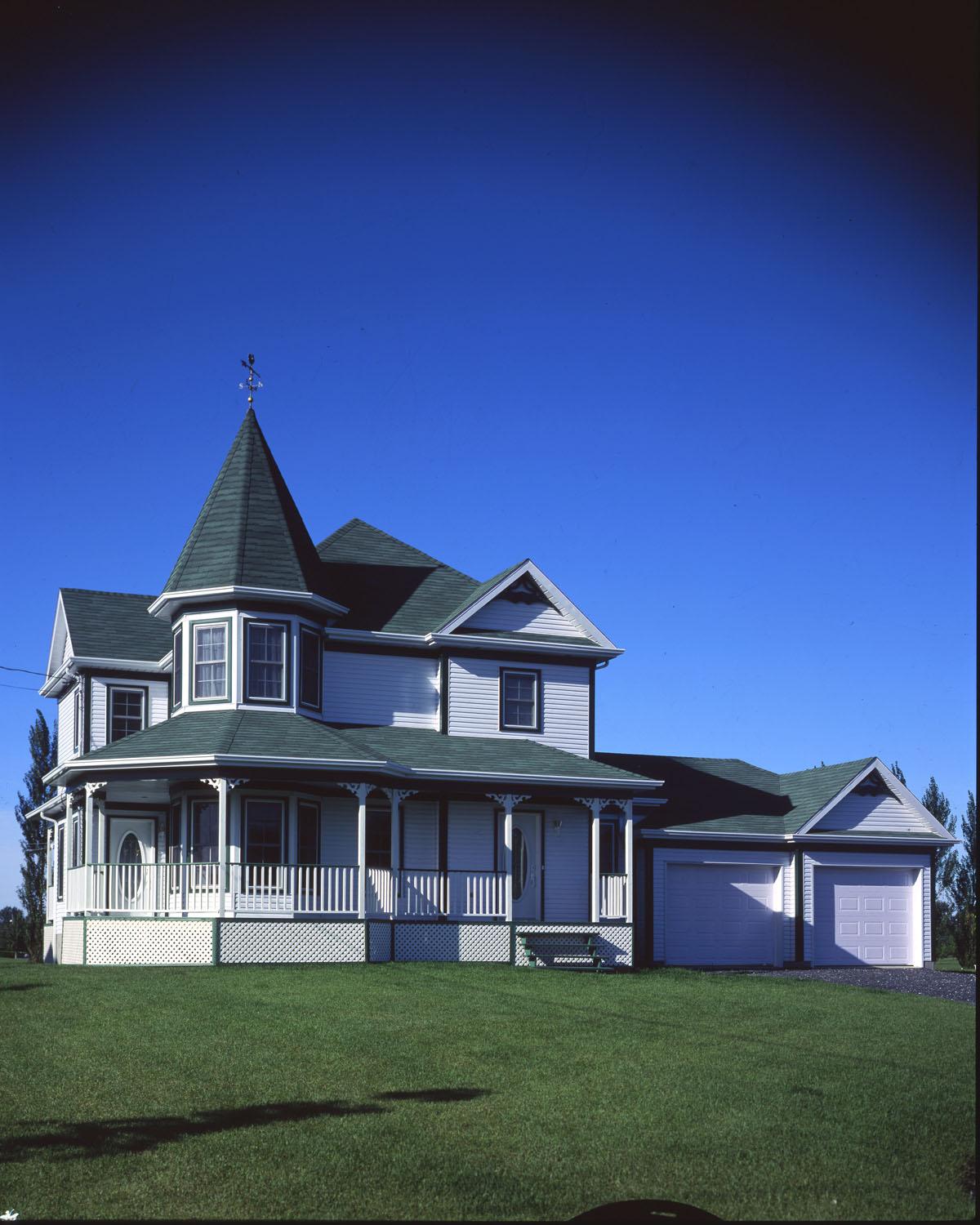 House plan exterior: Two-story home with a wraparound porch, gabled dormers, and a conical tower topped with a weather vane.