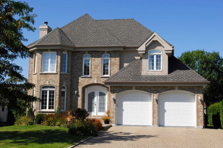 House plan exterior featuring a two-story brick home with a prominent gable, dual garage doors, and arched entry.