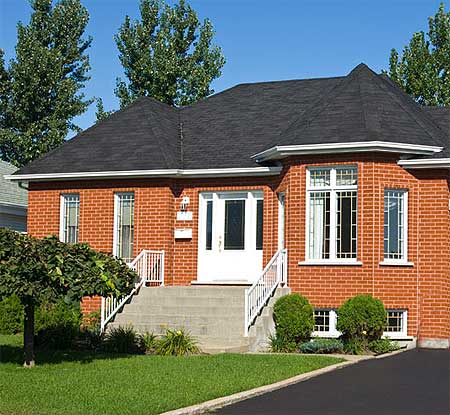 House plan exterior of a one-story brick home with a central entrance, white railings, and a multi-faceted roofline.