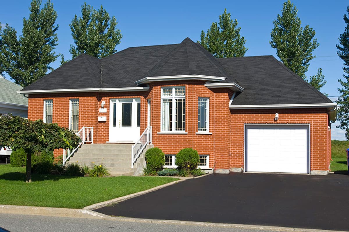 House plan exterior: Brick house with attached garage, central entrance with stairs, and multi-sided bay window.
