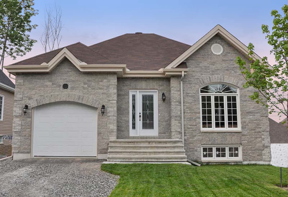 House plan exterior featuring stone facade, arched garage door, symmetrical gables, and arched window.