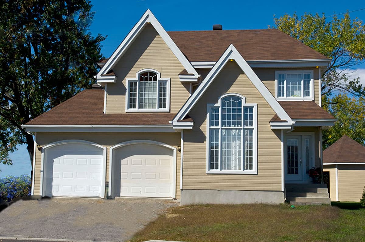 House plan exterior, two-story with a double garage, prominent gables, arched windows, and a covered entry.