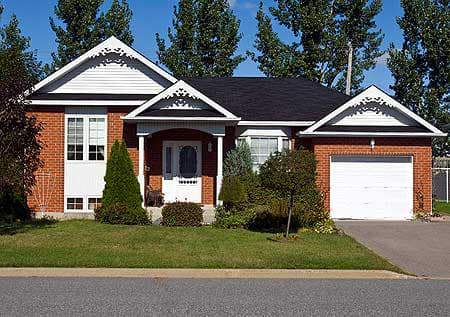 House plan exterior: One-story brick home with a covered entryway, gables with decorative trim, and an attached garage.