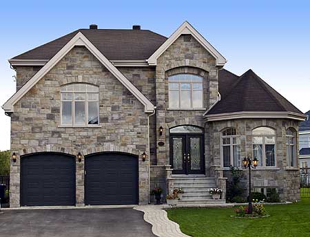 House plan exterior featuring stone facade, arched windows, double garage doors, and a prominent gabled roofline.