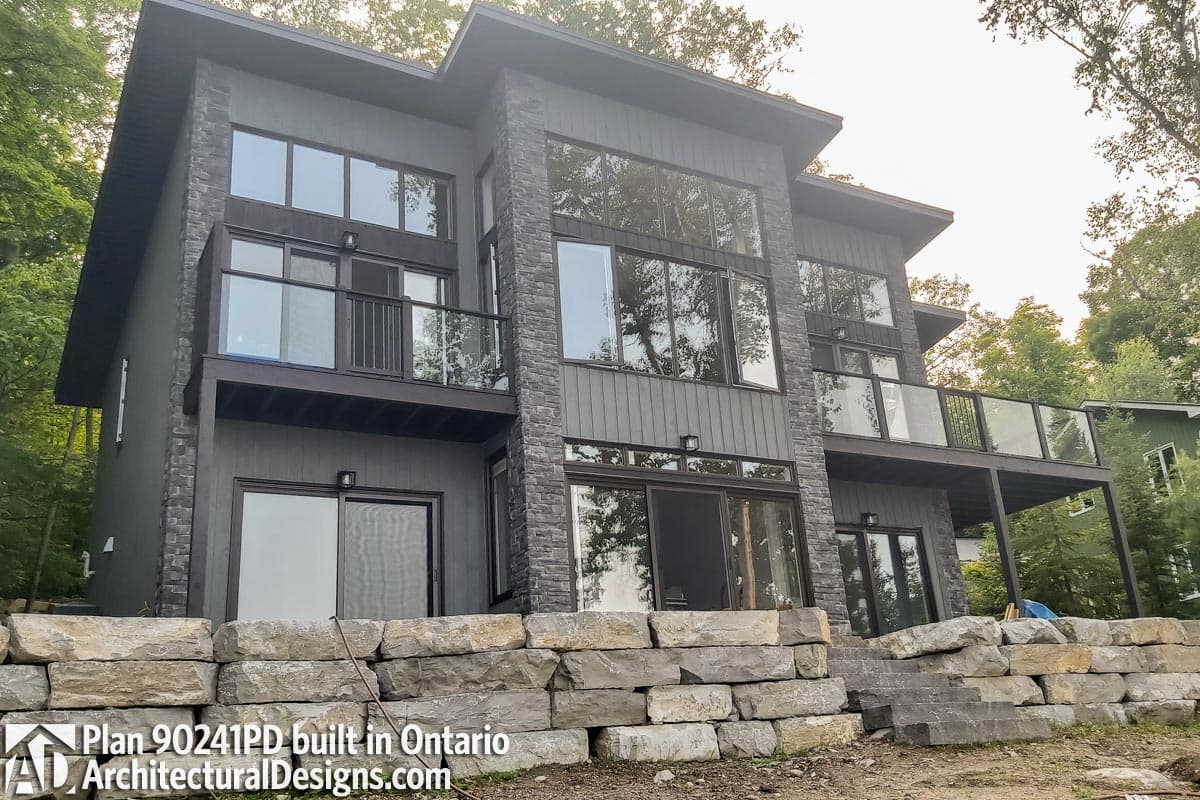 Modern two-story house plan exterior with stone accents, large windows, and balconies.