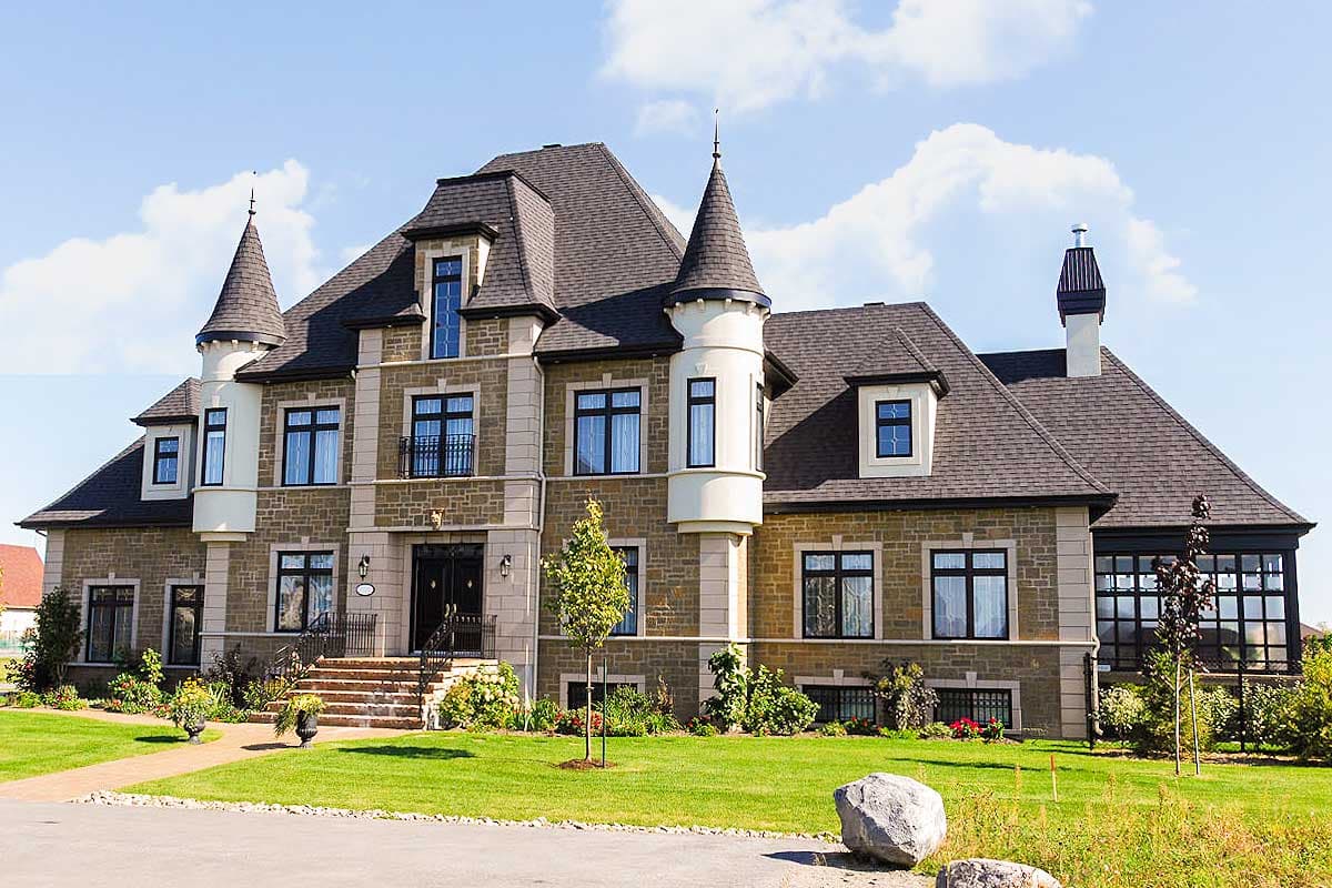 House plan exterior: French Chateau style, two stories, conical towers, stone facade, mansard roof, and central gabled dormers.