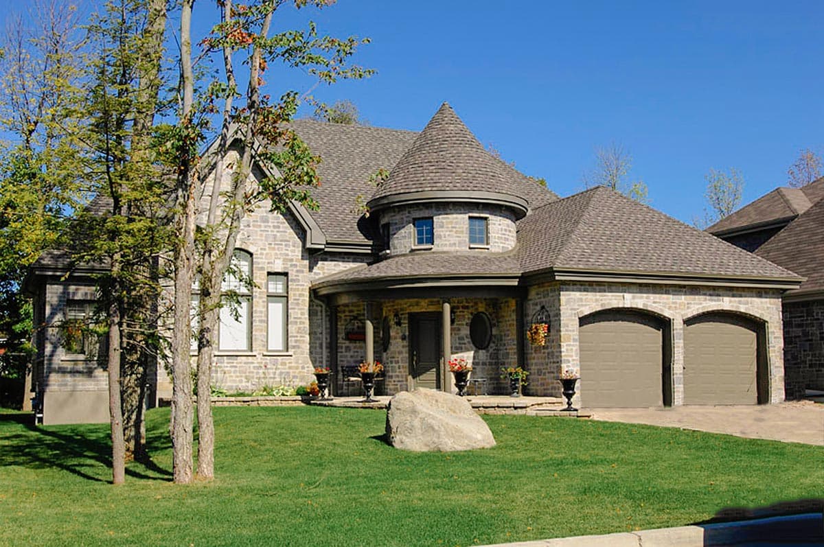 House plan exterior with stone facade, turret, arched entryway, and attached two-car garage.