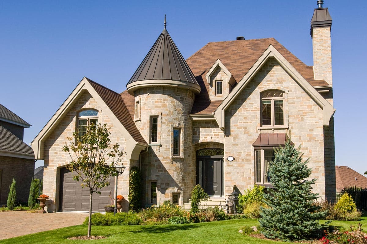 House plan exterior: stone facade, conical turret, dormers, and integrated garage.