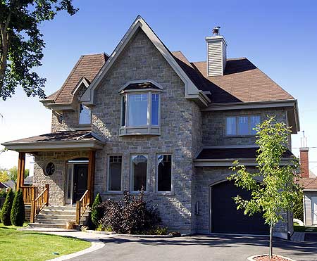 House plan exterior featuring stone facade, multiple gables, bay window, covered porch with wooden posts, and attached garage.