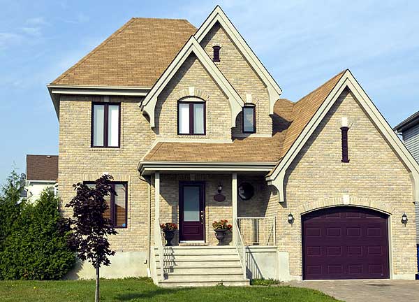 Two-story house plan exterior with brick facade, prominent gables, covered front porch, and arched garage door.