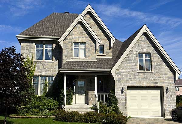 House plan exterior: Stone facade, two stories, covered porch, multiple gables, and attached garage.