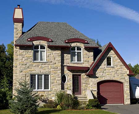 House plan exterior: Two-story stone home with a prominent stone chimney, arched dormers, and a side-facing garage with a red door.