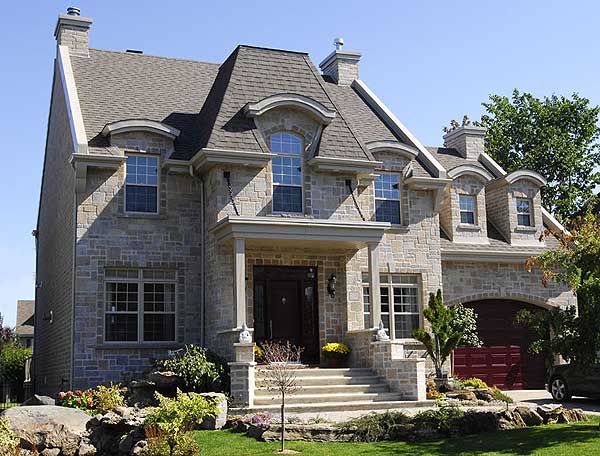 House plan exterior: stone facade, gabled roof, arched dormers, porte-cochère and integrated garage.