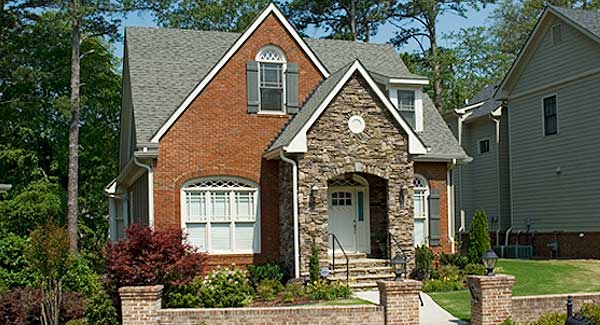 House plan exterior: Brick two-story with stone-accented arched entryway, gabled roof, and dormer window.