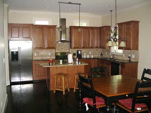 Kitchen featuring stainless steel refrigerator, granite island with seating, and dining table.