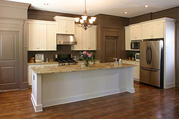 Kitchen with white cabinets, granite countertops, a large island with beadboard paneling, stainless steel appliances, and hardwood floors.