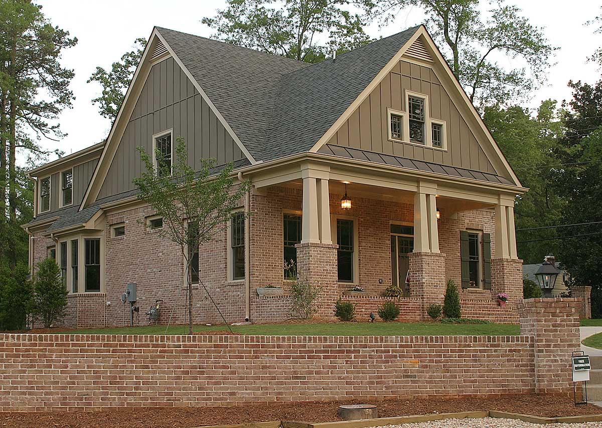 House plan exterior showing a two-story brick home with a covered front porch, gables, dormers, and a raised brick foundation.