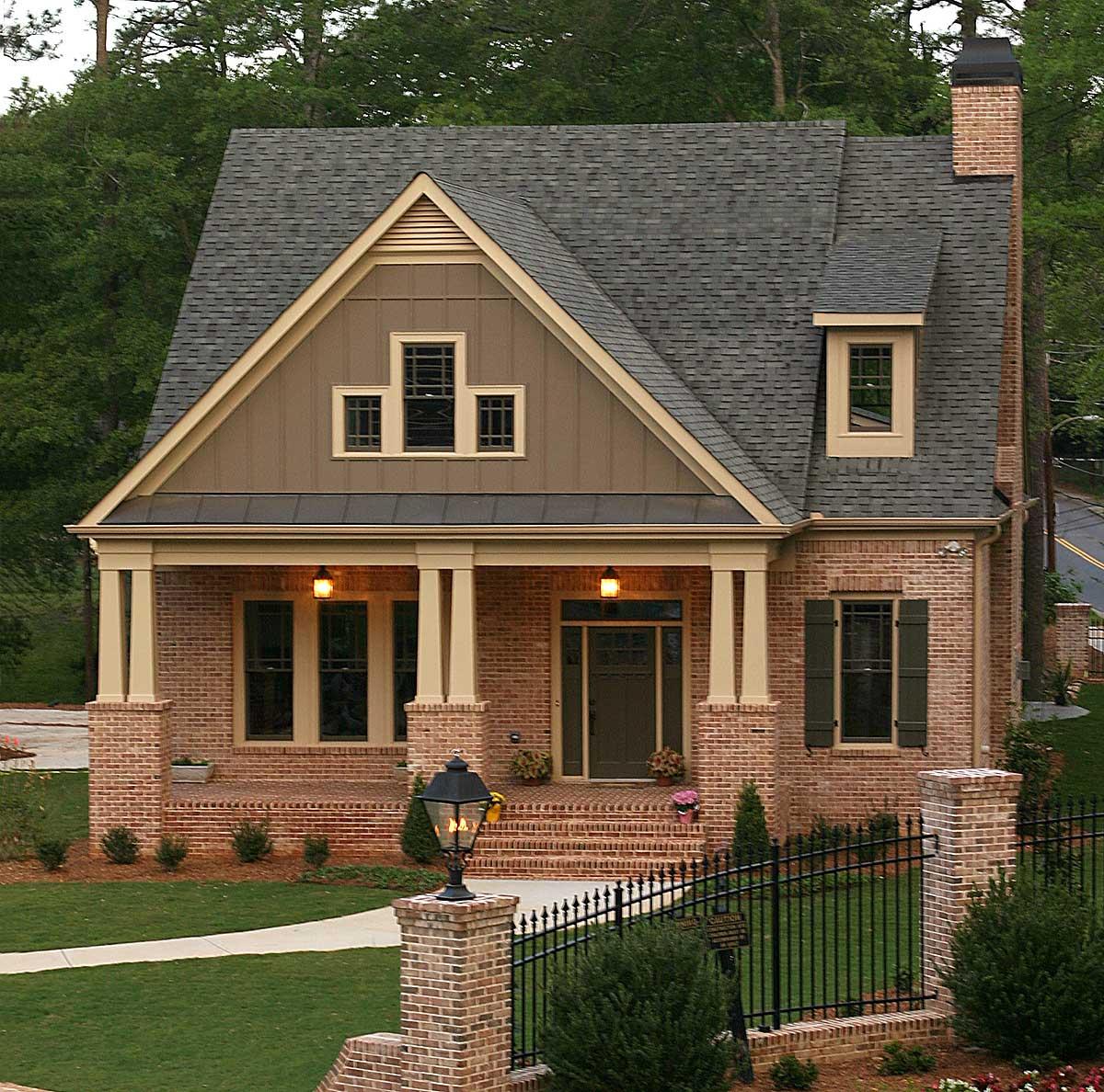 House plan exterior: Two-story brick home with covered porch, gables, dormer window, and prominent chimney.